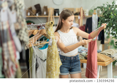 Girl chooses a set of clothes for summer. Visitor to the boutique examines the new summer collection of clothes 130394298
