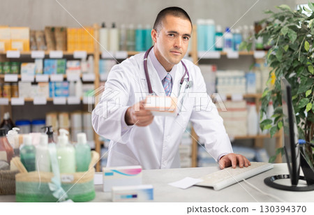 Male pharmacist standing at drugstore with medical product in hands Male pharmacist standing at drugstore with medical product in hands 130394370