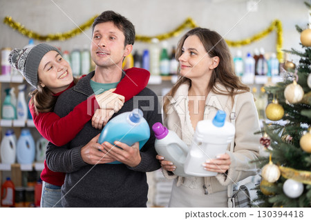 Couple man and woman with daughter choosing detergent in decorated store 130394418
