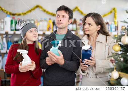 Father, mother and daughter choose detergent in supermarket Father, mother and daughter choose detergent in supermarket 130394457