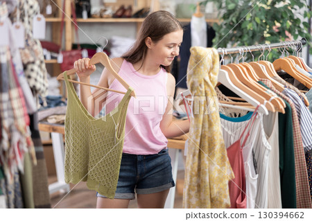 Teenage girl choosing top in clothing store Teenage girl choosing top in clothing store 130394662