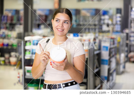 Cheerful young woman choosing painting materials in specialty store 130394685
