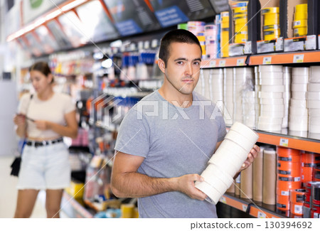 Man buy sticky adhesive tape in construction store for carrying out internal finishing work 130394692