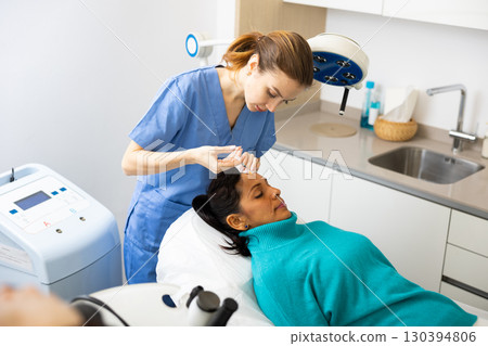 Woman patient receiving forehead injection at clinic Woman patient receiving forehead injection at clinic 130394806