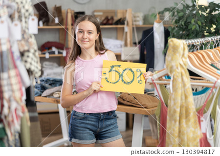 Teen girl holding discount sign in clothing store 130394817