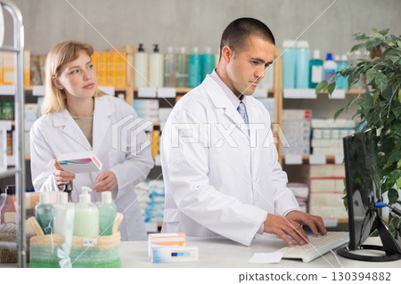 male pharmacist working on a computer in a pharmacy 130394882