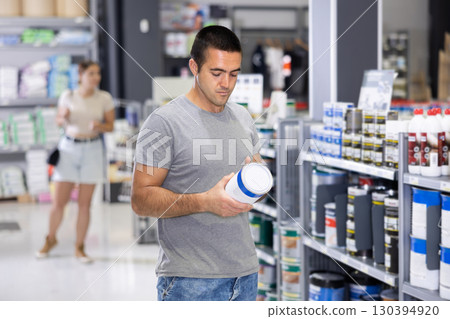 Male customer chooses can of paint in hardware store Male customer chooses can of paint in hardware store 130394920