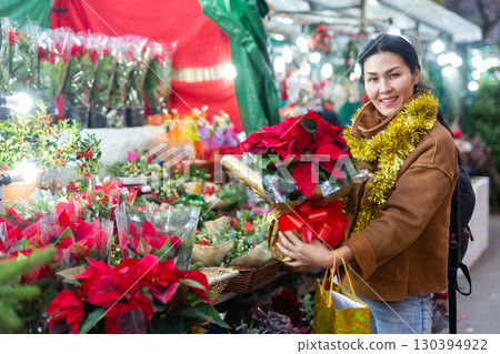 Woman choosing christmas bouquet flowers Poinsettias pulcherrima at street sale 130394922