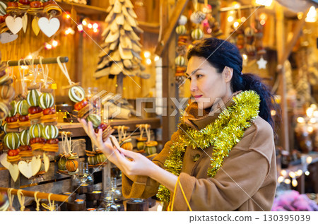 Asian female choosing decorations at Christmas fair Asian female choosing decorations at Christmas fair 130395039