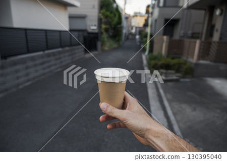 Coffee cup held up on quiet street 130395040