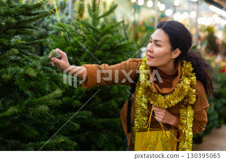 Woman customer buying fir tree at Christmas market Woman customer buying fir tree at Christmas market 130395065