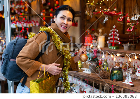 Woman chooses christmas balls at christmas street fair Woman chooses christmas balls at christmas street fair 130395068