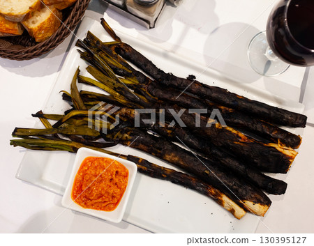Calcots onions served on plate with Romesco sauce - traditional Catalan dish Calcots onions served on plate with Romesco sauce - traditional Catalan dish 130395127