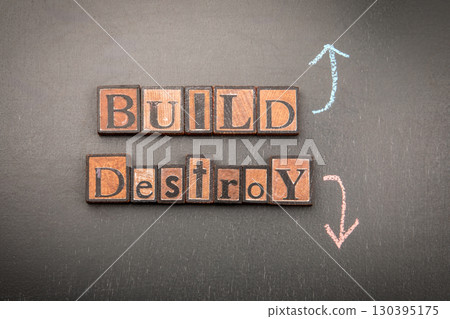 Build versus destroy concept with vintage wooden letter blocks and chalk arrows on blackboard 130395175