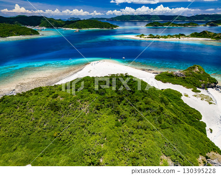 Drone footage of Kabi Island. Tourists are landing on the white sand beach. Parasols are set up, and boats and sabani boats are moored. 130395228
