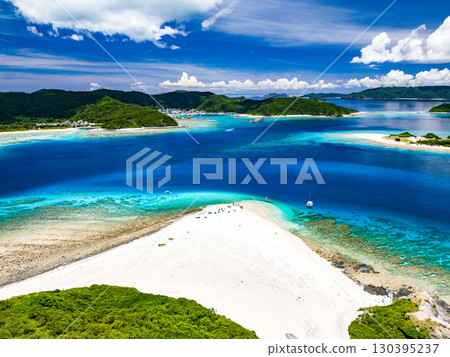 Drone footage of Kabi Island. Tourists are landing on the white sand beach. Parasols are set up, and boats and sabani boats are moored. Drone footage of Kabi Island. Tourists are landing on the white sand beach. Parasols are set up, and boats and sabani boats are moored. 130395237