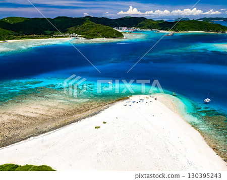 Drone footage of Kabi Island. Tourists are landing on the white sand beach. Parasols are set up, and boats and sabani boats are moored. Drone footage of Kabi Island. Tourists are landing on the white sand beach. Parasols are set up, and boats and sabani boats are moored. 130395243