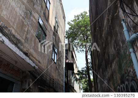 從泰國曼谷一條被建築物包圍的小巷中欣賞建築物、樹木和天空 130395270