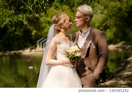 Newlyweds share a tender moment by the riverside in a serene natural setting 130395282