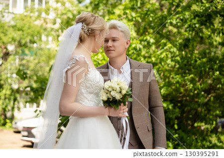 Wedding couple enjoying a moment in a lush green outdoor setting Wedding couple enjoying a moment in a lush green outdoor setting 130395291