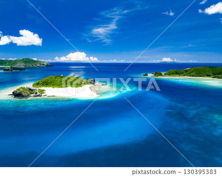 Drone shot of Kabi Island. Tourists are landing on the white sand beach. Parasols are set up, and boats and sabani boats are moored. 130395383