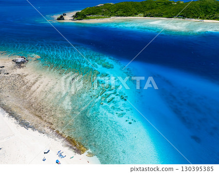 Drone shot of Kabi Island. Tourists are landing on the white sand beach. Parasols are set up, and boats and sabani boats are moored. 130395385