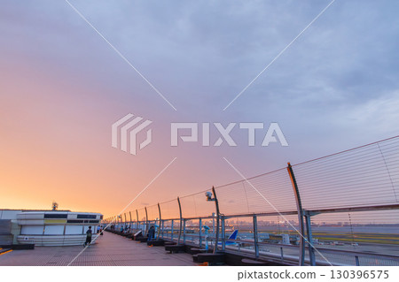 The deck of Haneda Airport at sunset. You can see passenger planes taking off and landing and the Tokyo cityscape at dusk. 2025 130396575