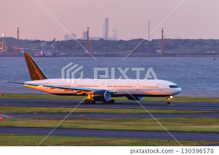 The deck of Haneda Airport at sunset. You can see passenger planes taking off and landing and the Tokyo cityscape at dusk. 2025 130396578