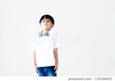 Elementary school boy standing in front of a white wall 130396653