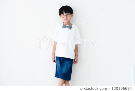 Elementary school boy standing in front of a white wall 130396654