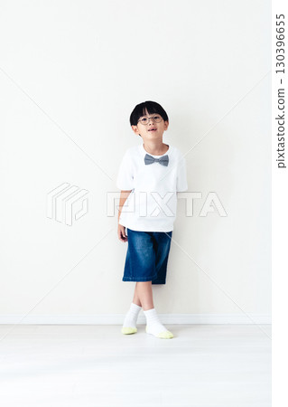 Elementary school boy standing in front of a white wall 130396655