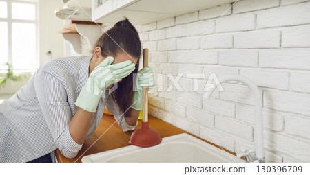 Sad Woman Facing Sink Blockage with Plunger 130396709