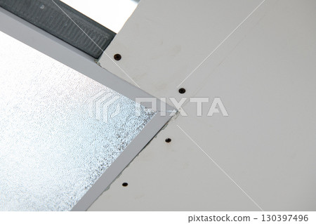 Close up detail of drywall installation during house renovation. construction work shows precise joining of plasterboard panel to metal corner bead near window Close up detail of drywall installation during house renovation. construction work shows precise joining of plasterboard panel to metal corner bead near window 130397496