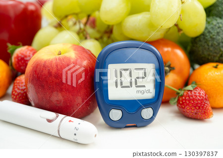 Asian hand holding digital glucose monitor measure with vegetable and fruit healthy food. 130397837