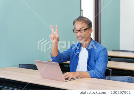 Senior man making a peace sign using a computer Senior man making a peace sign using a computer 130397901