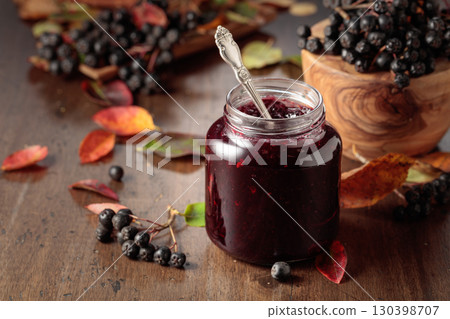 Chokeberry jam and fresh berries on an old wooden table. 130398707
