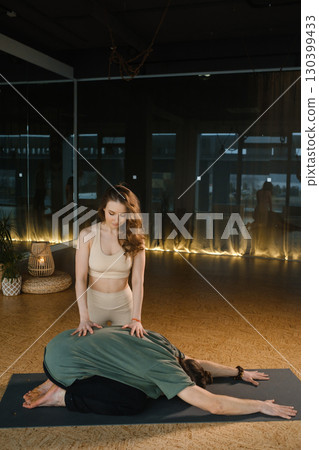Couple practicing yoga and meditation in a tranquil studio with soft lighting during a peaceful evening session 130399433