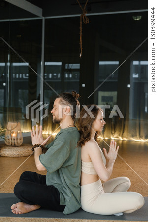 Yoga practice with a partner in a serene indoor studio at sunset focusing on mindfulness and connection 130399444