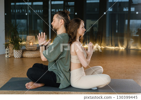 Yoga practice with a partner in a serene indoor studio at sunset focusing on mindfulness and connection 130399445