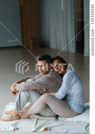 Couple enjoying a quiet moment together in a serene indoor space on a soft mat during a peaceful afternoon Couple enjoying a quiet moment together in a serene indoor space on a soft mat during a peaceful afternoon 130399446