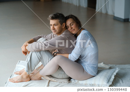 Couple enjoying a quiet moment together in a serene indoor space on a soft mat during a peaceful afternoon Couple enjoying a quiet moment together in a serene indoor space on a soft mat during a peaceful afternoon 130399448