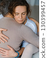 Couple engaging in a warm embrace during a morning meditation session in a bright, serene studio space 130399457