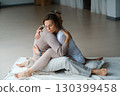 Couple engaging in a warm embrace during a morning meditation session in a bright, serene studio space 130399458
