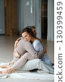 Couple engaging in a warm embrace during a morning meditation session in a bright, serene studio space 130399459