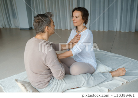 Couples engaging in mindfulness practice during a wellness retreat in a serene studio setting focused on emotional connection and relaxation techniques 130399461