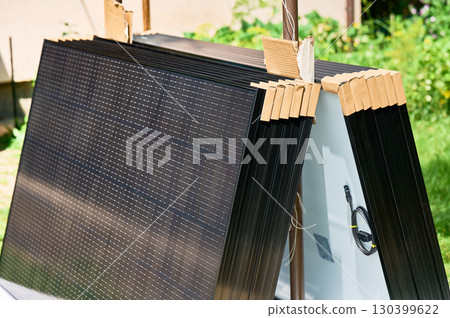 Stack of new solar panels with protective cardboard, ready for installation. Renewable energy, sustainable home improvements, and eco-friendly investments in residential property infrastructure. 130399622