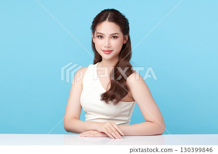 A beautiful young Asian woman with clean, fresh skin against a blue background. Skincare, facial treatment, cosmetology, beauty, and spa. An elegant portrait of an Asian woman. A beautiful young Asian woman with clean, fresh skin against a blue background. Skincare, facial treatment, cosmetology, beauty, and spa. An elegant portrait of an Asian woman. 130399846