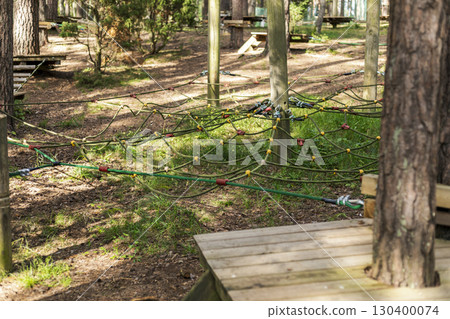 This tree climbing park features a network of ropes and climbing structures situated among tall trees, providing a fun and safe environment for outdoor activities 130400074