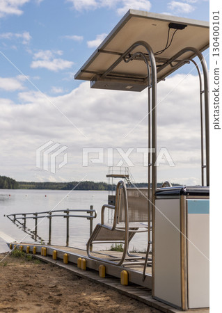 A specially designed sliding chair is situated on the sandy shore, allowing disabled individuals easy access to the water's edge 130400101