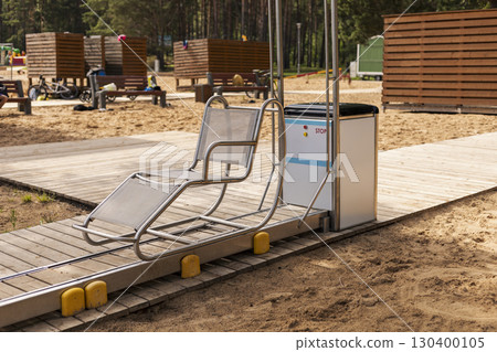 A specially designed sliding chair is placed on a wooden pathway at a beach, providing a seamless way for disabled users to access the sea comfortably and safely 130400105